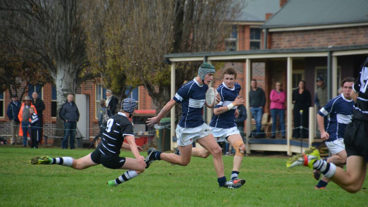 MAKING A RUN: Joe Kingham evades the defence of Newington College’s Massimo Marchese in TAS’ rugby win on Saturday. 